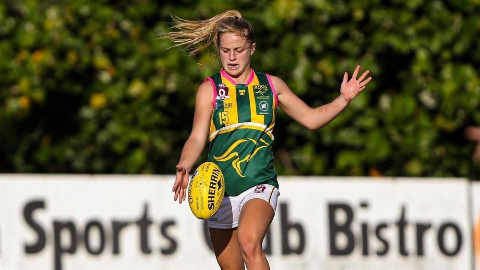 Belle Dawes wearing IDA women's cleats punts the ball in an AFLW match