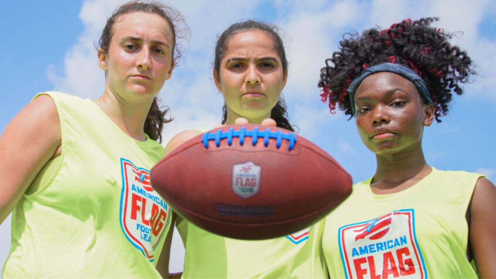 Photo of 3 women holding a football. Source: American Flag Football