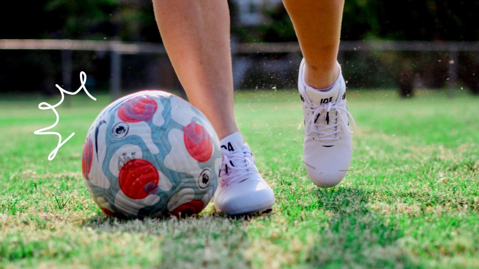 Close up of players feet dribbling a soccer ball on grass wearing IDA Centra women's white soccer cleats